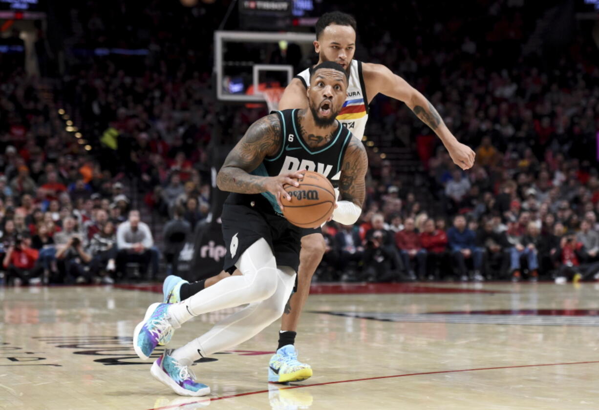 Portland Trail Blazers guard Damian Lillard, front, looks to pass the ball as Minnesota Timberwolves forward Kyle Anderson, rear, defends during the second half of an NBA basketball game in Portland, Ore., Saturday, Dec. 10, 2022. The Blazers won 124-118.