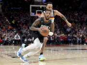 Portland Trail Blazers guard Damian Lillard, front, looks to pass the ball as Minnesota Timberwolves forward Kyle Anderson, rear, defends during the second half of an NBA basketball game in Portland, Ore., Saturday, Dec. 10, 2022. The Blazers won 124-118.