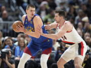 Denver Nuggets center Nikola Jokic, left, looks to drive to the rim as Portland Trail Blazers forward Drew Eubanks defends in the first half of an NBA basketball game Friday, Dec. 23, 2022, in Denver.