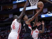 Portland Trail Blazers guard Anfernee Simons (1) lays up a shot between Houston Rockets forwards Usman Garuba (16) and Tari Eason (17) during the first half of an NBA basketball game Saturday, Dec. 17, 2022, in Houston.