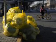 A cyclist passes by household waste inside yellow trash bags marked as medical waste in Beijing, Wednesday, Dec. 7, 2022. In a sharp reversal, China has announced a series of measures rolling back some of the most draconian anti-COVID-19 restrictions.