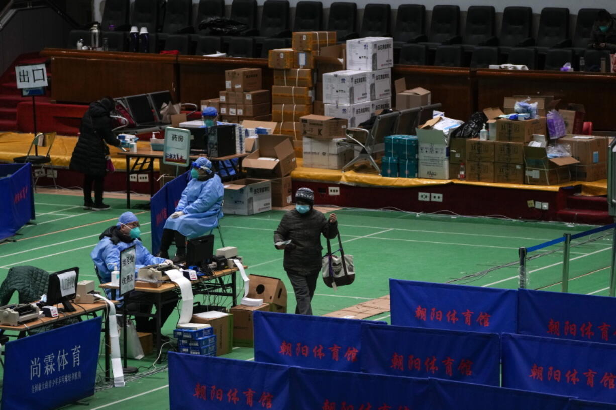 Medical workers tend to residents at a gymnasium converted into a fever clinic in Beijing, Sunday, Dec. 18, 2022. Deaths linked to the coronavirus are appearing in Beijing after weeks of China reporting no fatalities, even as the country is seeing a surge of cases.