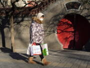 A resident wearing mask past by a traditional entrance way in Beijing, Friday, Dec. 16, 2022. A week after China dramatically eased some of the world's strictest COVID-19 containment measures, uncertainty remained Thursday over the direction of the pandemic in the world's most populous nation.