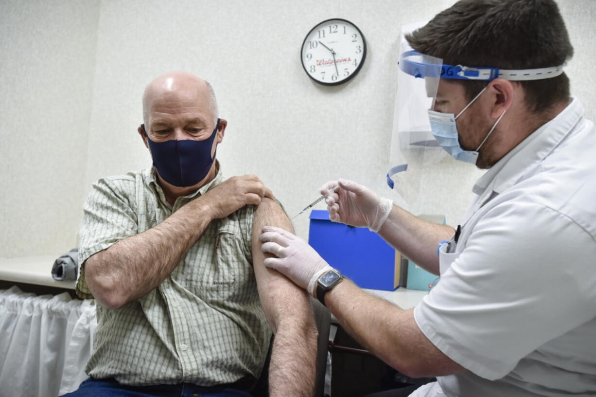 FILE - In this April 1, 2021, file photo Gov. Greg Gianforte receives a shot of the Pfizer COVID-19 vaccine from pharmacist Drew Garton at a Walgreen's pharmacy, in Helena, Mont. Medical providers and Montana residents with compromised immune systems are challenging the only law in the U.S. that prevents state employers from mandating workers get vaccinated amid a surge of COVID-19 infections. They argue the new law violates federal requirements for safe workplaces and reasonable accommodations for people with disabilities and want a federal judge to rule that it doesn't apply to hospitals and other medical providers.