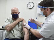 FILE - In this April 1, 2021, file photo Gov. Greg Gianforte receives a shot of the Pfizer COVID-19 vaccine from pharmacist Drew Garton at a Walgreen's pharmacy, in Helena, Mont. Medical providers and Montana residents with compromised immune systems are challenging the only law in the U.S. that prevents state employers from mandating workers get vaccinated amid a surge of COVID-19 infections. They argue the new law violates federal requirements for safe workplaces and reasonable accommodations for people with disabilities and want a federal judge to rule that it doesn't apply to hospitals and other medical providers.