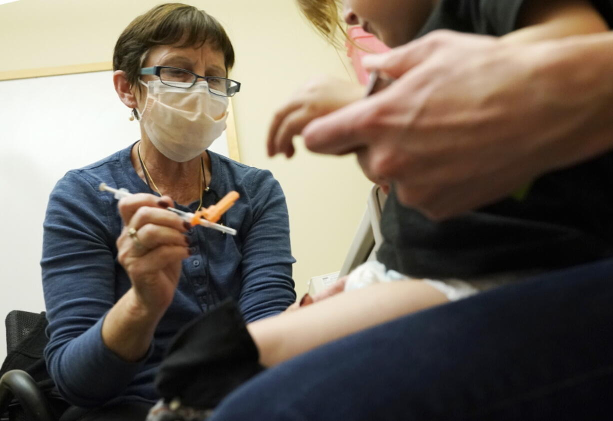 Deborah Sampson, left, a nurse at a University of Washington Medical Center clinic in Seattle, gives a Pfizer COVID-19 vaccine shot to a 20-month-old child, June 21, 2022, in Seattle. The U.S. on Thursday, Dec. 8, 2022 open doses of the updated COVID-19 vaccines for most children younger than age 5. The Food and Drug Administration's decision aims to better protect the littlest kids from severe COVID-19 at a time when children's hospitals already are packed with tots suffering a variety of other respiratory illnesses, too. (AP Photo/Ted S.