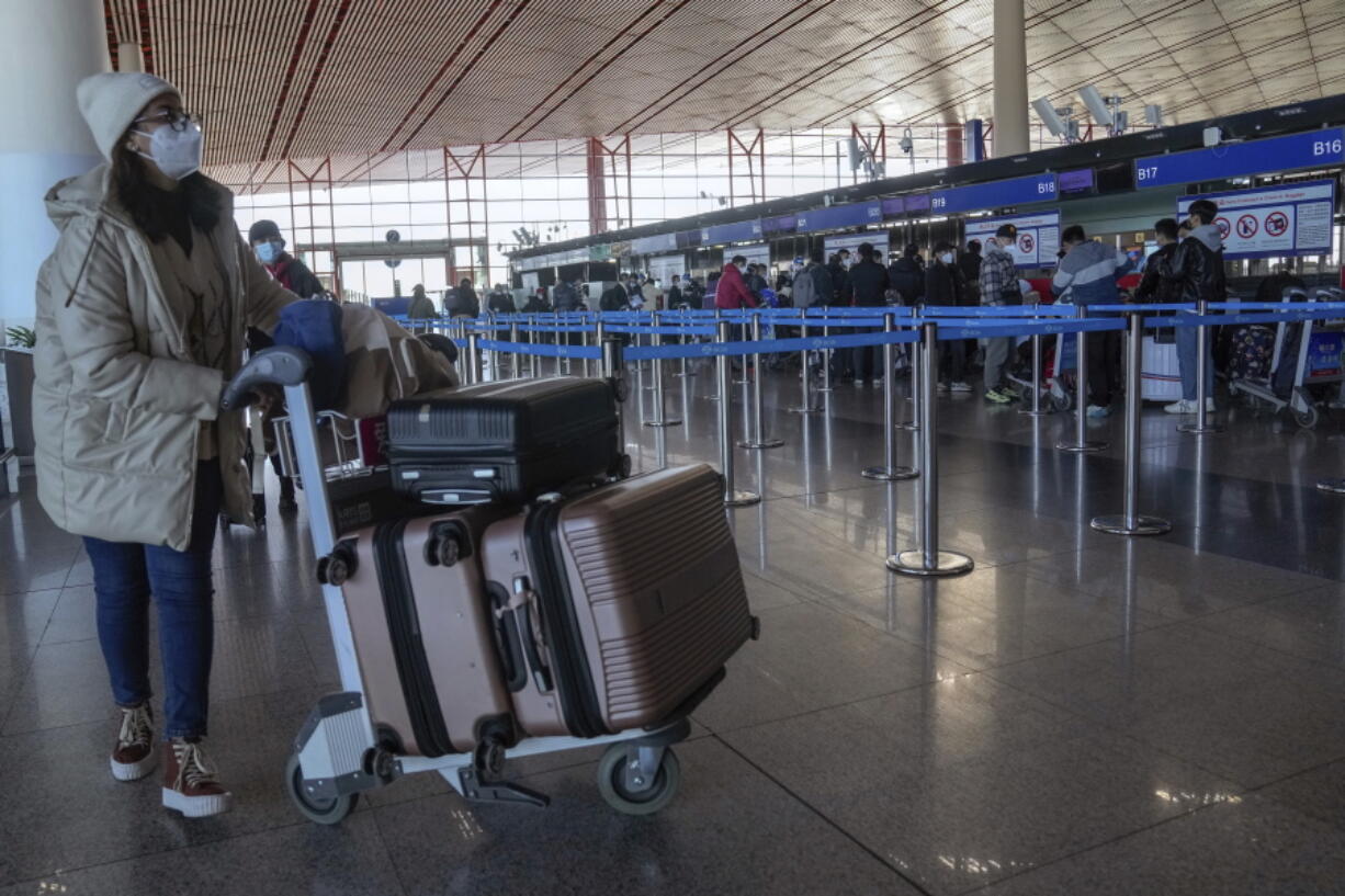 A masked traveller arrives at the international flight check in counter at the Beijing Capital International Airport in Beijing, Thursday, Dec. 29, 2022. Moves by the U.S., Japan and others to mandate COVID-19 tests for passengers arriving from China reflect global concern that new variants could emerge in its ongoing explosive outbreak -- and the government may not inform the rest of the world quickly enough.