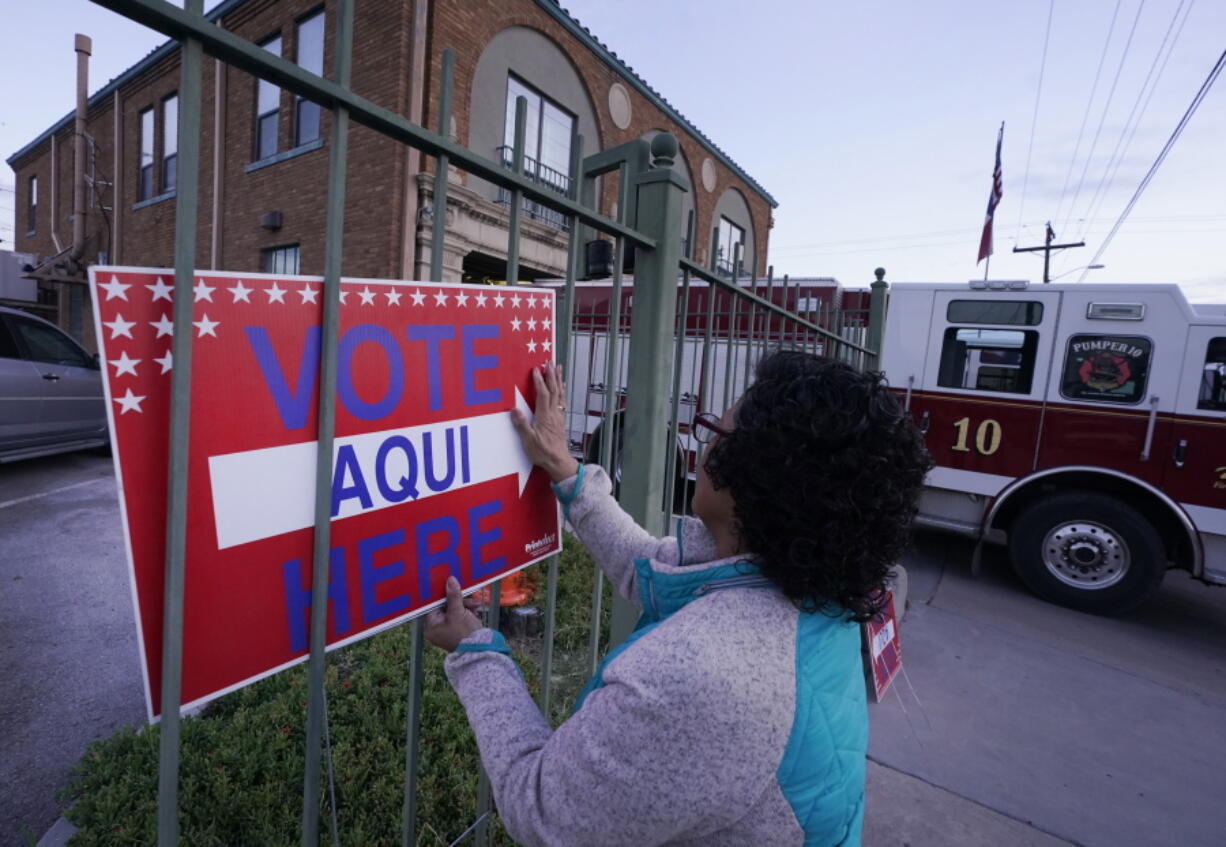 FILE - Election worker Ramona Ortiz places a sign outside a polling station at Fire Station 3 on E. Rio Grande Ave in El Paso, Texas, just before polls open on Nov. 8, 2022. Next year is shaping up to be another busy for state legislatures seeking to change voting laws.