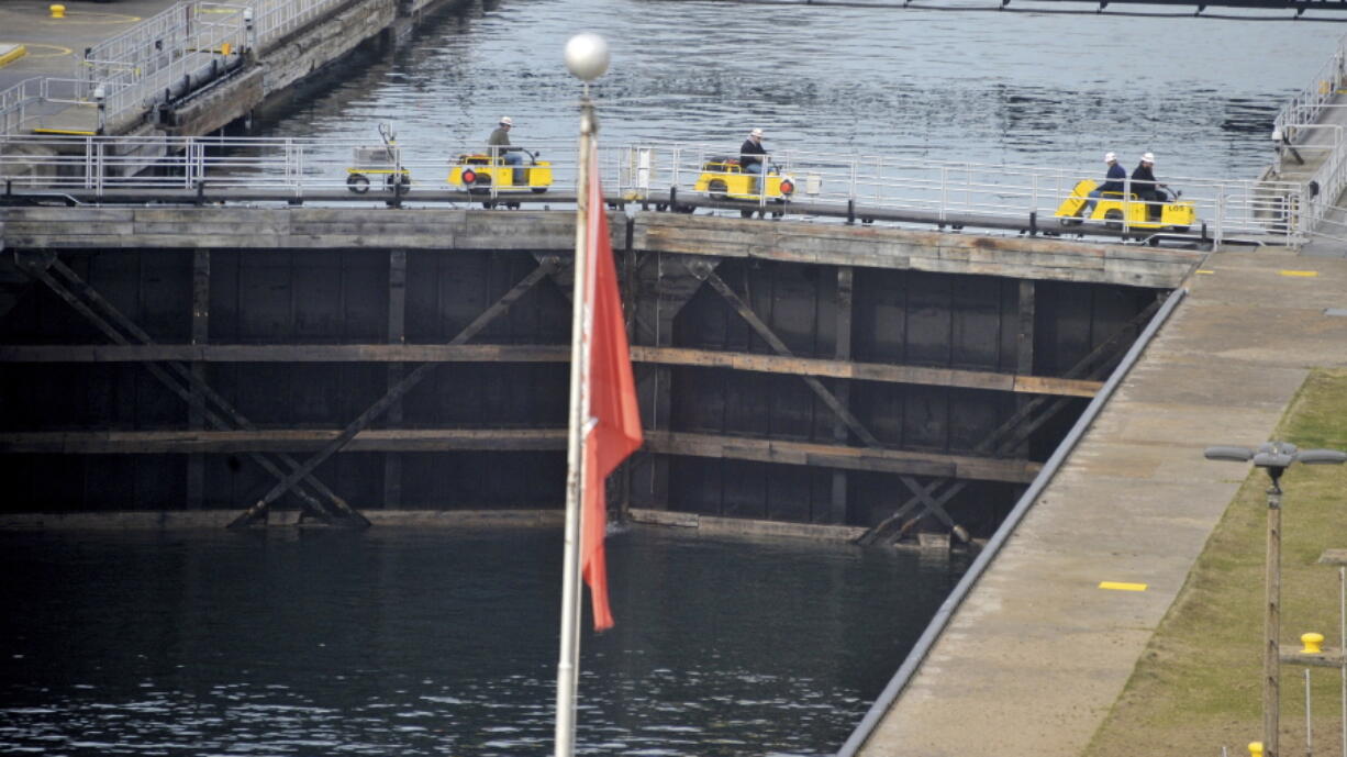 FILE - Workers use scooters across the closed gate of the MacArthur lock on April 18, 2016, at the Soo Locks outside Sault Ste Marie, Mich. President Joe Biden signed on Friday, Dec. 23, 2022, a large defense bill that includes the Water Resources Development Act of 2022. The water legislation sets out new infrastructure projects for the Army Corps of Engineers to build, including a new Soo Lock. (Dale G.