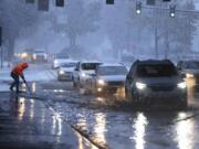 A worker from Washington Department of Transportation clears a drain on Northgate Way during a heavy snow at the morning commute in Seattle, on Tuesday, Dec. 20, 2022.