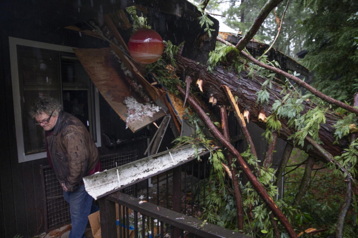 Bill Lance leaves his home Tuesday after a windstorm blew a tree onto the roof destroying much of his condominium in Eugene, Ore.