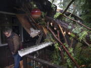 Bill Lance leaves his home Tuesday after a windstorm blew a tree onto the roof destroying much of his condominium in Eugene, Ore.