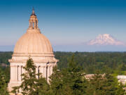 Aerial shot of the state capitol building in Olympia, Washington on a summer afternoon, with the snowy mass of Mt Rainier/Tahoma in the distance.