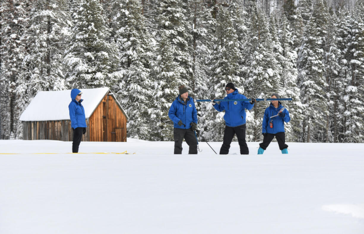 Second from the right, Sean de Guzman Chief of the California Department of Water Resources Snow Surveys and Water Supply Forecasting Section, Andy Reising, right, and Anthony Burdock left, both California Department of Water Resources Engineers in the Snow Surveys and Water Supply Forecasting Unit, work the measurement phase of the first media snow survey of the 2023 season, as California Department of Water Resources Director Karla Nemeth watches the survey at the Phillips Station site in the Sierra Nevada Mountains. The survey is held approximately 90 miles east of Sacramento off Highway 50 in El Dorado County on Jan. 3, 2023.