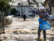 Residents scramble to retrieve belongings before flood waters rise too high in Merced, California, on Jan. 10, 2023.