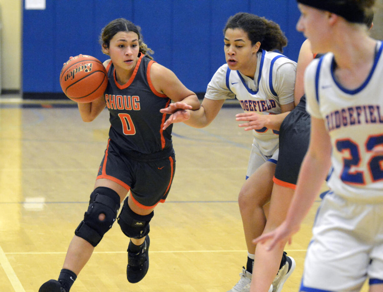 Washougal’s Chloe Johnson (0) looks to dribble past Ridgefield defender Janessa Chatman on Tuesday, Jan. 24, 2023, at Ridgefield High School.