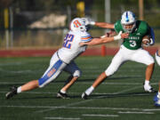 Mountain View senior Kyle Chen, right, stiff arms Ridgefield senior Brody Masterson on Friday, Sept. 9, 2022, during the Thunder's 26-20 triple overtime win against Ridgefield at McKenzie Stadium.