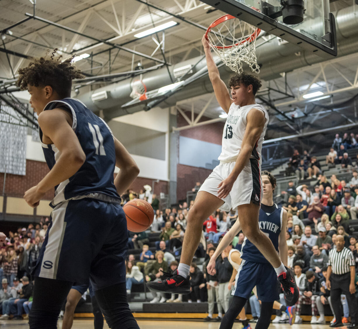 Union senior Yanni Fassilis, right, hangs off the rim after a dunk Friday, Jan. 6, 2023, during the Titans’ 61-41 win against Skyview at Union High School.