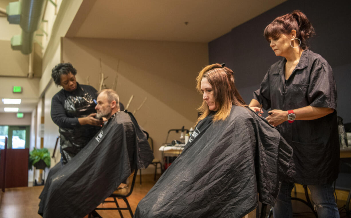 The Barbers hairstylists Debi Norman, right, and Lynell Felix, left, cut the hair of Alicia Haddix, second from right, and Arthur Walton, on Thursday as part of Project Homeless Connect at St. Joseph Catholic Church. The event brings multiple services under one roof for a day to help out those experiencing homelessness.