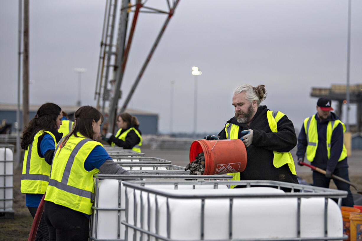 Volunteer Harley Fowler, with bucket, pours a layer of rocks into a Grattix box at the Port of Vancouver last week. The boxes will be given for free to some businesses along the Columbia River.