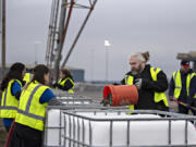 Volunteer Harley Fowler, with bucket, pours a layer of rocks into a Grattix box at the Port of Vancouver last week. The boxes will be given for free to some businesses along the Columbia River.