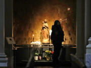 Kia Green lights a candle at St. James Cathedral, the Cathedral for the Catholic Archdiocese of Seattle, in an otherwise nearly empty sanctuary where hours have been limited because of the coronavirus outbreak Saturday, March 28, 2020, in Seattle.