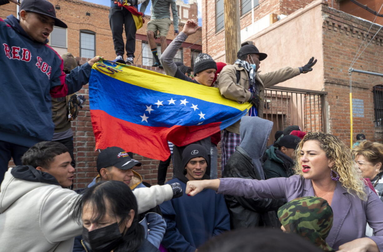 A migrant, far left, reaches to bump fists with a local resident demonstrating in support of migrants in downtown El Paso, Texas, Saturday, Jan. 7, 2023. Several hundred marched through the streets of El Paso a day before President Joe Biden's first, politically-thorny visit to the southern border.