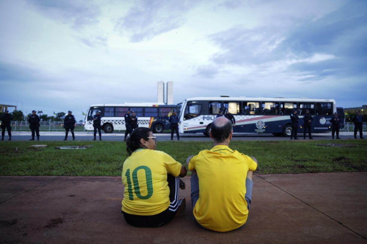 A couple of supporters of former President Jair Bolsonaro observe the movement of military police during an abortive protest organized by supporters of former President Jair Bolsonaro, in Brasilia, Brazil, Wednesday, Jan. 11, 2023. Despite being widely announced by social media, the protests did not take place and did not have supporters of the former president.