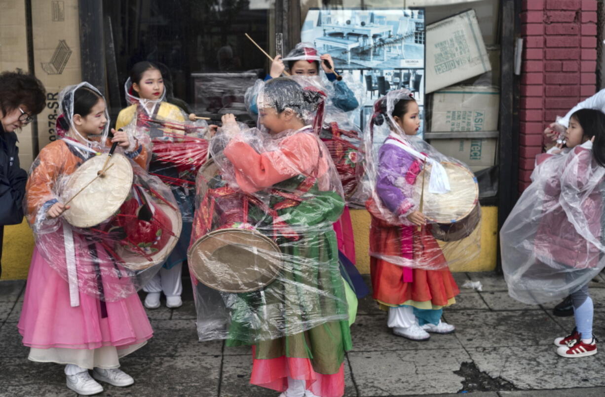 The Kim Eung Hwa Korean Dance Academy students put on protective rain coats prior to participating in the Kingdom Day Parade in Los Angeles, Monday, Jan. 16, 2023. A barrage of atmospheric river storms has dumped rain and snow on California since late December, cutting power to thousands, swamping roads, unleashing debris flows, and triggering landslides. Monday's system is relatively weak compared with earlier storms.