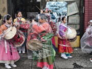 The Kim Eung Hwa Korean Dance Academy students put on protective rain coats prior to participating in the Kingdom Day Parade in Los Angeles, Monday, Jan. 16, 2023. A barrage of atmospheric river storms has dumped rain and snow on California since late December, cutting power to thousands, swamping roads, unleashing debris flows, and triggering landslides. Monday's system is relatively weak compared with earlier storms.