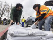 Fernando Bizarro, left, collects sandbags from an emergency distribution center to prepare for an upcoming storm, Tuesday, Jan. 3, 2023, in San Francisco.