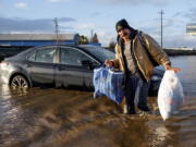 Jesus Torres carries belongings from his flooded Merced, Calif., home on Tuesday, Jan. 10, 2023.