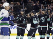 Seattle Kraken right wing Oliver Bjorkstrand (22) is congratulated by right wing Eeli Tolvanen (20) and defenseman Adam Larsson, second from right, after scoring against the Vancouver Canucks during the first period of an NHL hockey game, Wednesday, Jan. 25, 2023, in Seattle.