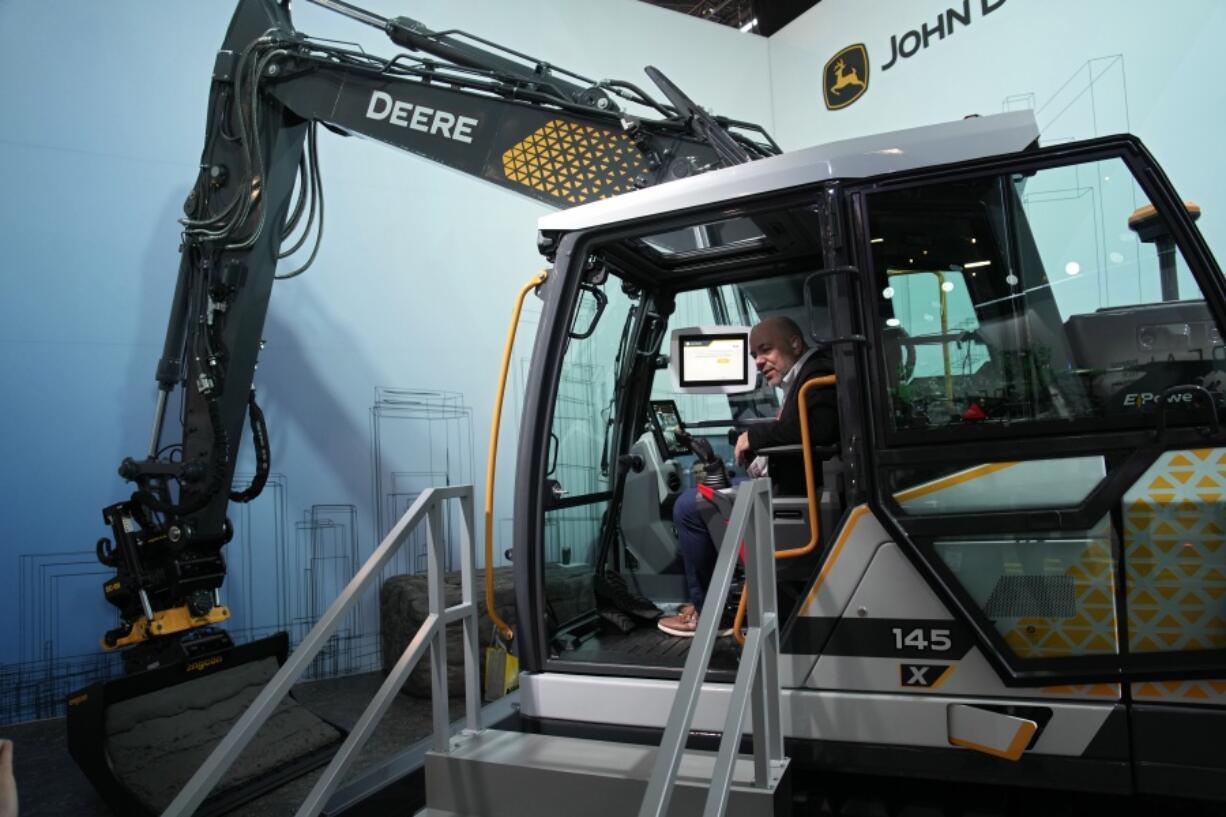 People look at a John Deere electric excavator at the John Deere booth during the CES tech show Friday, Jan. 6, 2023, in Las Vegas.