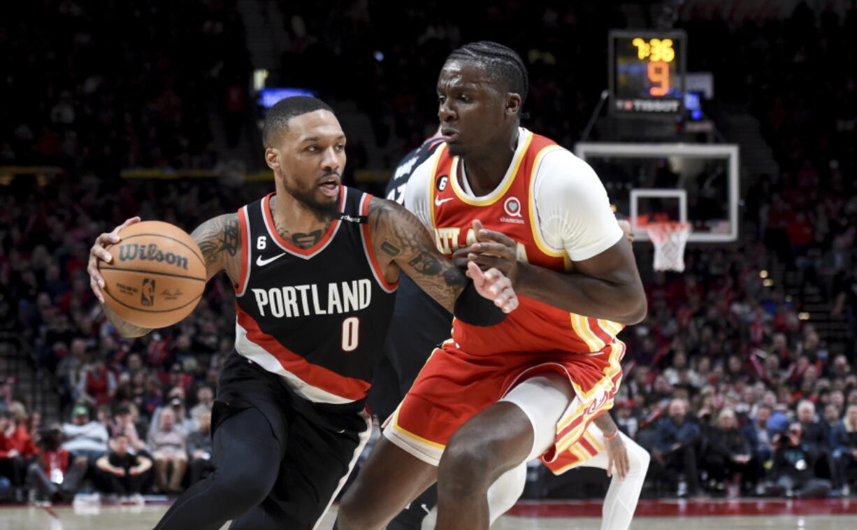 Portland Trail Blazers guard Damian Lillard, left, drives to the basket on Atlanta Hawks center Clint Capela, right, during the second half of an NBA basketball game in Portland, Ore., Monday, Jan. 30, 2023. The Blazers won 129-125.