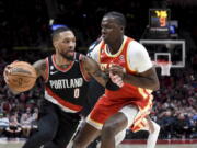 Portland Trail Blazers guard Damian Lillard, left, drives to the basket on Atlanta Hawks center Clint Capela, right, during the second half of an NBA basketball game in Portland, Ore., Monday, Jan. 30, 2023. The Blazers won 129-125.