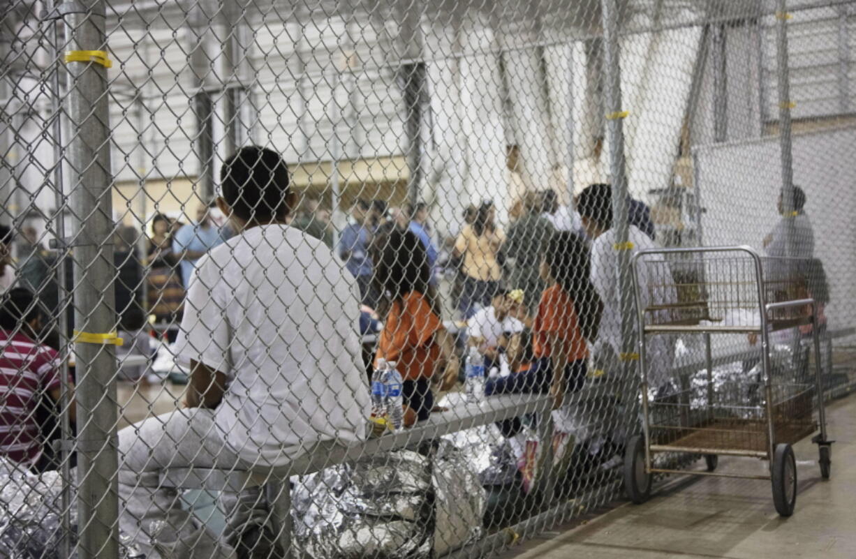 FILE - In this photo provided by U.S. Customs and Border Protection, people who've been taken into custody related to cases of illegal entry into the United States, sit in one of the cages at a facility in McAllen, Texas, on June 17, 2018. As thousands of children were taken from their parents at the southern border amid a crackdown on illegal crossings by the Trump administration, a federal public defender in San Diego set out to find new strategies to go after the longstanding deportation law fueling the family separations. (U.S.