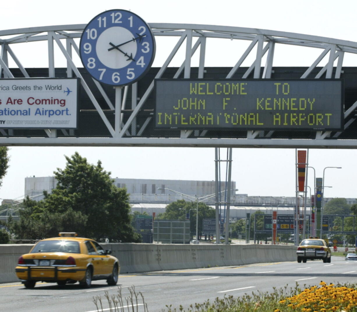 FILE - A clock at the entrance to JFK Airport in New York is pictured on Aug. 15, 2003. Officials are investigating a close call at the New York airport that happened Friday, Jan. 13, 2023, between a plane that was crossing a runway and another that was preparing for takeoff.