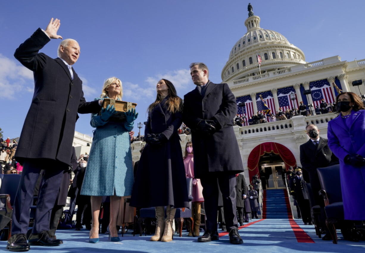 FILE - Joe Biden is sworn in as the 46th president of the United States by Chief Justice John Roberts as Jill Biden holds the Bible during the 59th Presidential Inauguration at the U.S. Capitol in Washington, Jan. 20, 2021, as their children Ashley and Hunter watch. The ocean blue tweed dress and matching coat that Jill Biden wore for Joe Biden's presidential inauguration is about to go on display at the Smithsonian's National Museum of American History. In a rare move, the museum will also display the ensemble she wore for evening inaugural events, an ivory silk wool dress and matching cashmere coat.