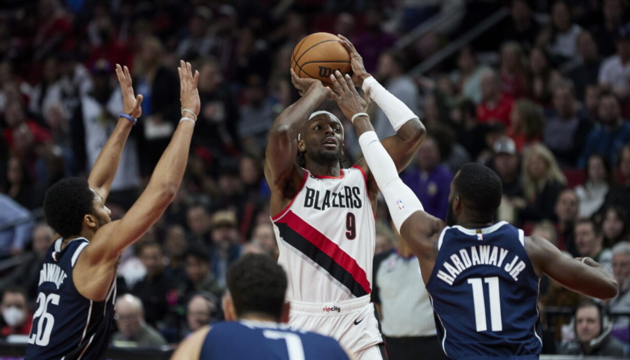 Portland Trail Blazers forward Jerami Grant shoots as Dallas Mavericks forward Tim Hardaway Jr., right, and guard Spencer Dinwiddie defend during the second half of an NBA basketball game in Portland, Ore., Saturday, Jan. 14, 2023.