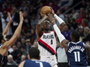 Portland Trail Blazers forward Jerami Grant shoots as Dallas Mavericks forward Tim Hardaway Jr., right, and guard Spencer Dinwiddie defend during the second half of an NBA basketball game in Portland, Ore., Saturday, Jan. 14, 2023.