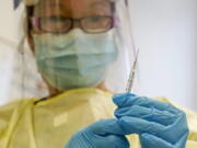 FILE - A physician assistant prepares a syringe with the Mpox vaccine for a patient at a vaccination clinic in New York on Friday, Aug. 19, 2022.  Mpox is no longer the exploding health crisis that it appeared to be less than six months ago. So who deserves the credit for controlling the U.S. outbreak?