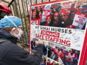 FILE - Zach Clapp, a nurse in the Pediatric Cardiac ICU at Mount Sinai Hospital signs a board demanding safe staffing during a rally by NYSNA nurses from NY Presbyterian and Mount Sinai, Tuesday, March 16, 2021, in New York. Negotiations to keep 10,000 New York City nurses from walking off the job headed Friday, Jna. 6, 2023, into a final weekend as some major hospitals braced for a potential strike by sending ambulances elsewhere and transferring such patients as vulnerable newborns.