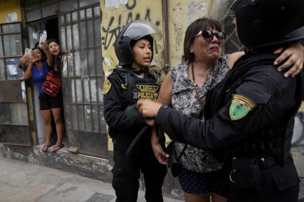 Police confort a neighbor who was harassed by anti-government protesters outside the San Marcos University in Lima, Peru, Saturday, Jan. 21, 2023. Police evicted from the university grounds protesters who arrived from Andean regions seeking the resignation of President Dina Boluarte, the release from prison of ousted President Pedro Castillo and immediate elections.