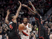 Portland Trail Blazers guard Damian Lillard, center drives to the basket against Toronto Raptors forwards Precious Achiuwa, left, and Chris Boucher during the second half of an NBA basketball game in Portland, Ore., Saturday, Jan. 28, 2023. Toronto won 123-105.