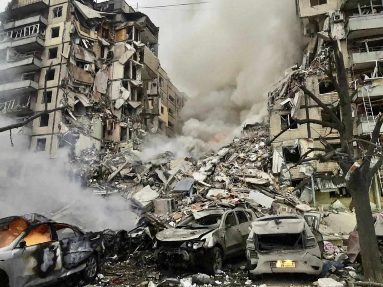 In this photo released by the Dnipro Regional Administration, smoke rises after a Russian rocket hit a multistory building leaving many people under debris in Dnipro, Ukraine, Saturday, Jan. 14, 2023.