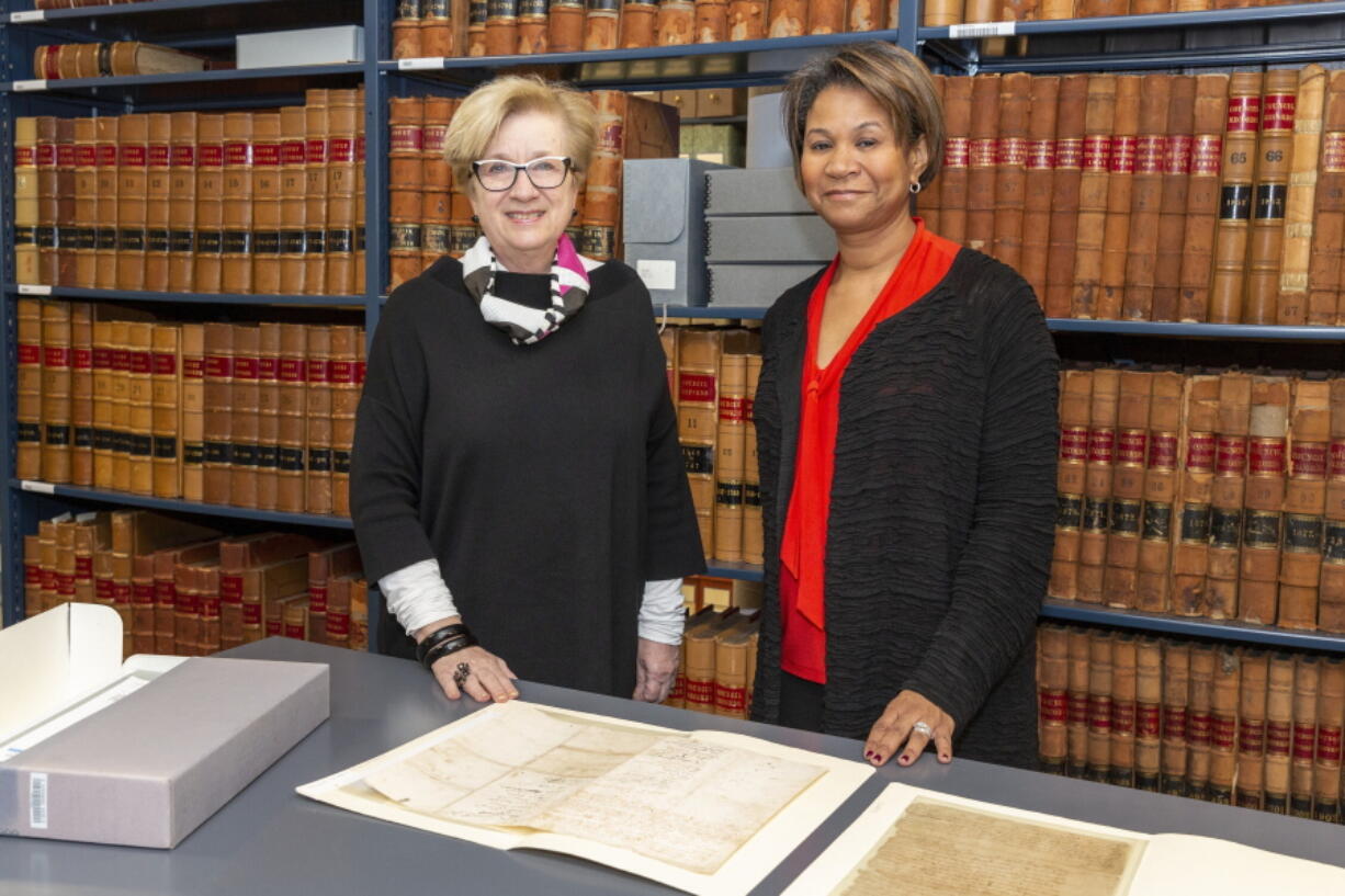 In this image provided by the Peabody Essex Museum, Lynda Roscoe Hartigan, PEM's Rose-Marie and Eijk van Otterloo Executive Director and CEO, left, and Massachusetts Supreme Judicial Court Chief Justice Kimberly S. Budd pose with Salem Witch Trial documents from 1692 at the Massachusetts Archives in Boston. Hundreds of court documents from Salem Witch Trials are being transferred from the museum, where they have been stored for more than four decades, to the newly expanded Judicial Archives facility.