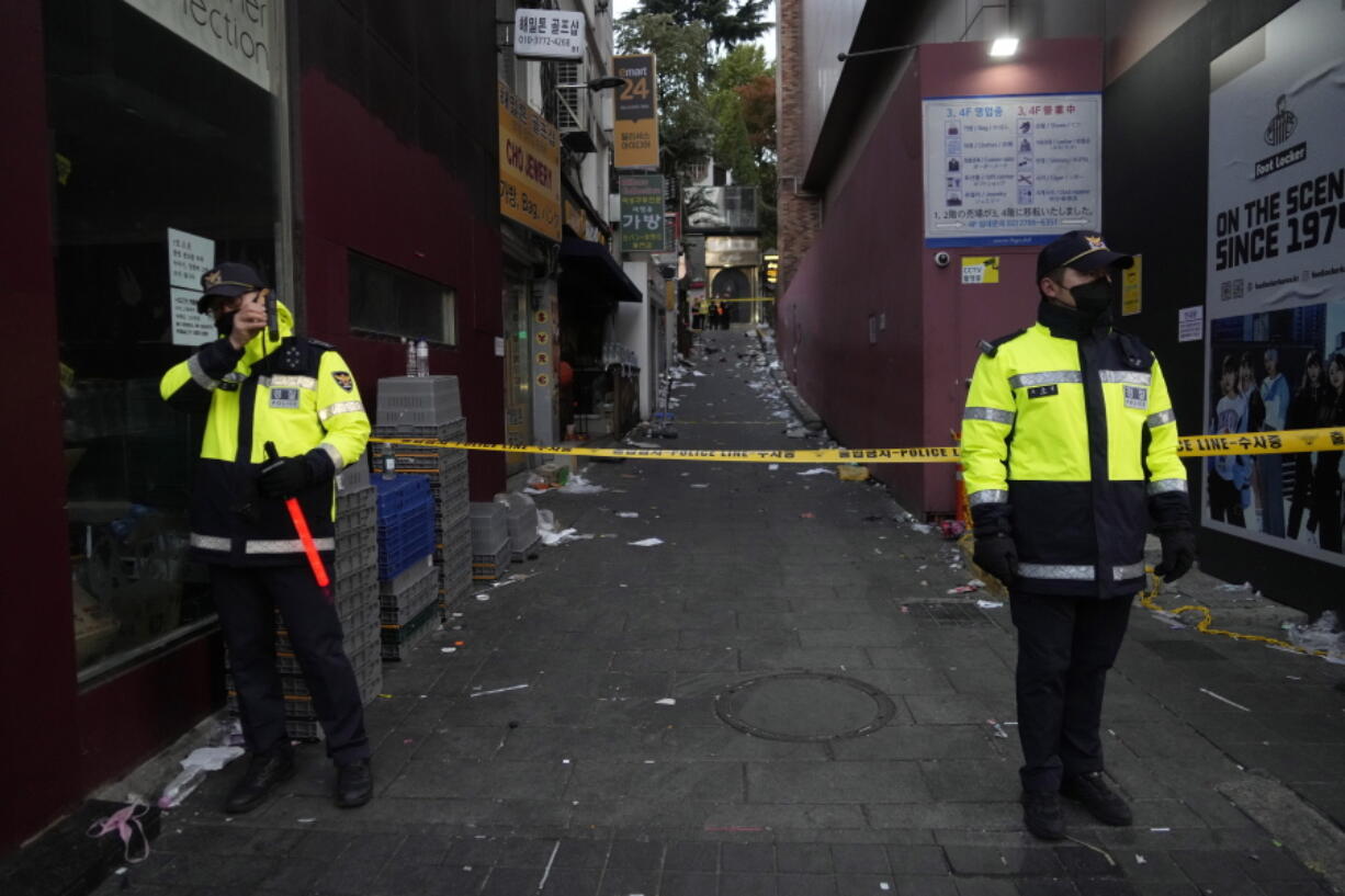 FILE- Police officers stand guard at the scene where dozens of people died and were injured during a crowd surge in Seoul, South Korea, on Oct. 30, 2022. South Korean police on Friday, Jan. 13, 2023, said they are seeking charges of involuntary manslaughter and negligence against 23 officials, for a lack of safety measures they said were responsible for a crowd surge that killed nearly 160 people in October.