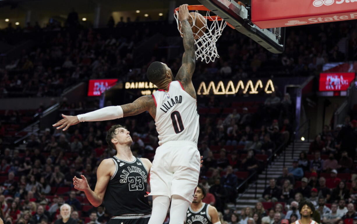 Portland Trail Blazers guard Damian Lillard (0) dunks over San Antonio Spurs forward Zach Collins (23) during the second half of an NBA basketball game in Portland, Ore., Monday, Jan. 23, 2023.