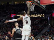 Portland Trail Blazers guard Damian Lillard (0) dunks over San Antonio Spurs forward Zach Collins (23) during the second half of an NBA basketball game in Portland, Ore., Monday, Jan. 23, 2023.